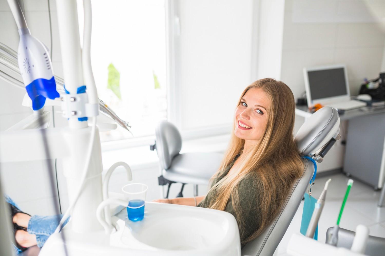 A woman sitting in a dental chair, receiving dental treatment from a dentist.